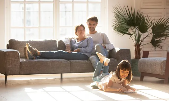 couple in couch and daughter in floor playing